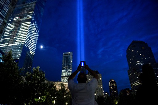 A man photographs beams of light symbolizing the two World Trade Center towers the night before the 15th anniversary of the September 11, 2001 terrorist attacks in the United States on September 10, 2016 in New York, New York. / AFP PHOTO / Brendan Smialowski