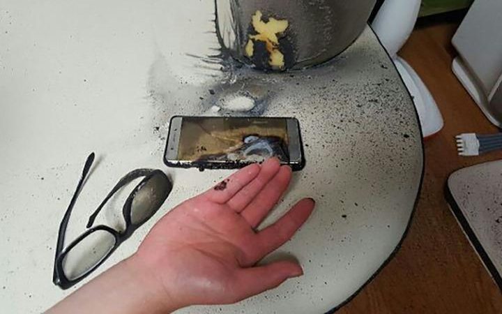  This blown up Samsung Note 7 handset is pictured next to a blistered hand Credit: AFP 